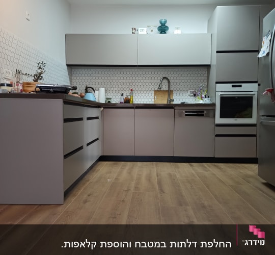 מטבח מודרני עם ארונות אפורים ורצפת עץ